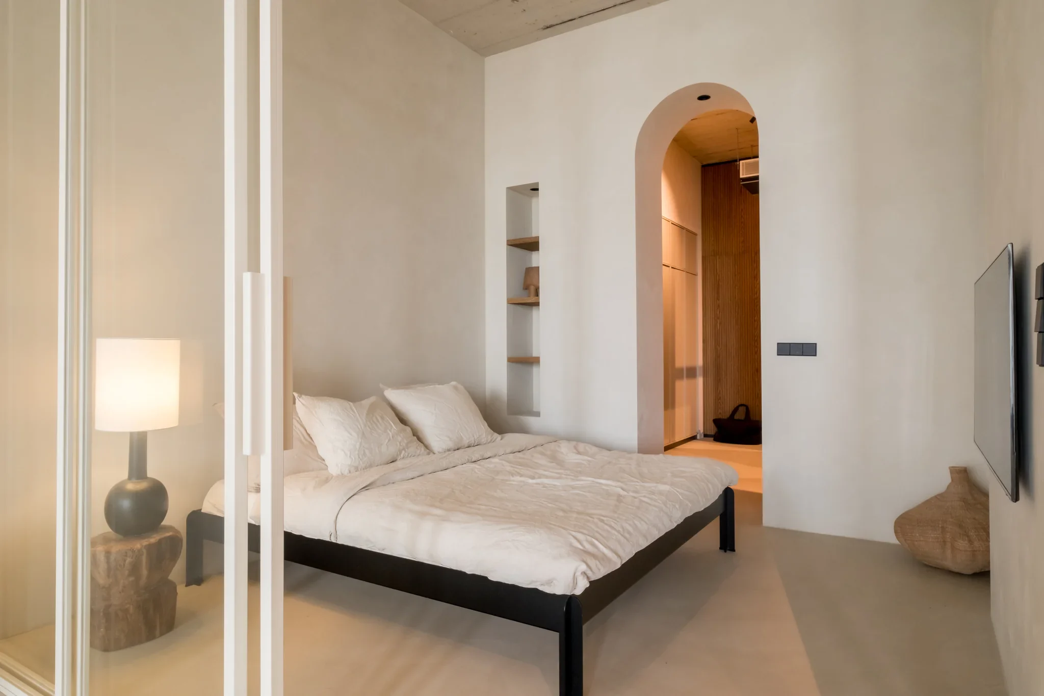 Woningfotografie in Haarlem van slaapkamer met zwart bedframe en boogvormige doorgang