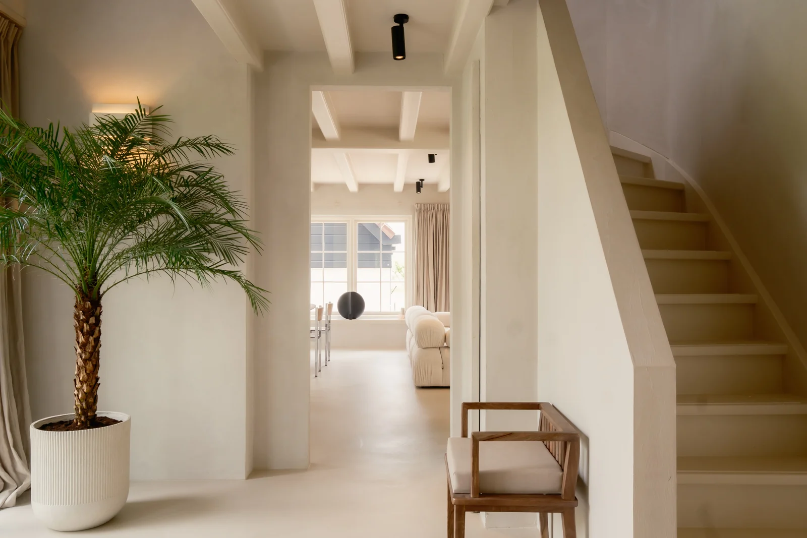 Woningfotografie Vinkeveen van lichte hal met houten trap, plant en zicht op woonkamer